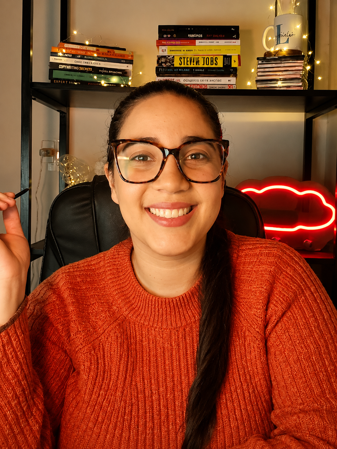 Fundadora da Amarella sorrindo no estúdio, cercada por livros e luz quente